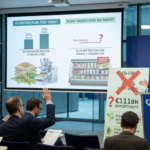 A press conference at the European Commission headquarters in 2026 showing a presentation screen comparing the EU's 35% animal feed protein target against the lack of targets for plant-based human food, with a speaker addressing the policy backlash.